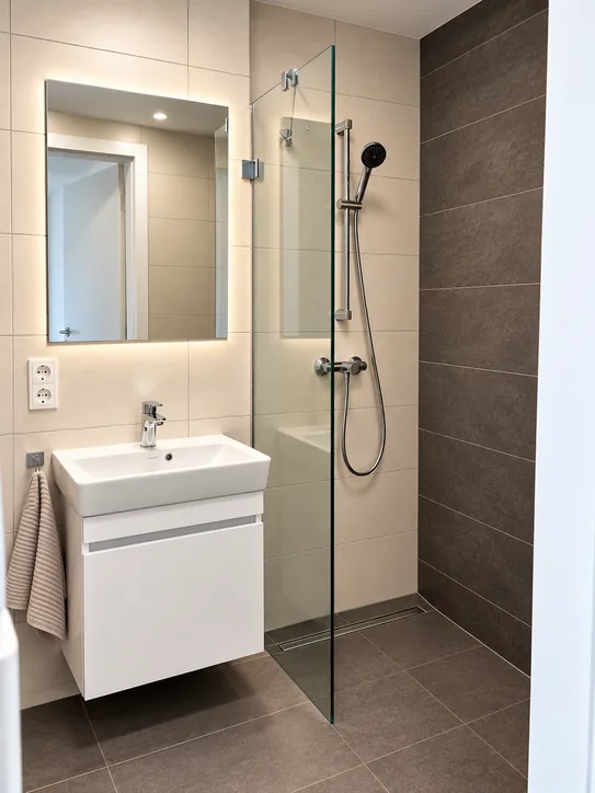 Duschbad mit bodengleicher Dusche, Glaswand und Waschtisch mit beleuchtetem Spiegel