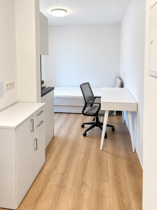 Wohn- und Schlafbereich mit Bett, Schreibtisch und Bürostuhl