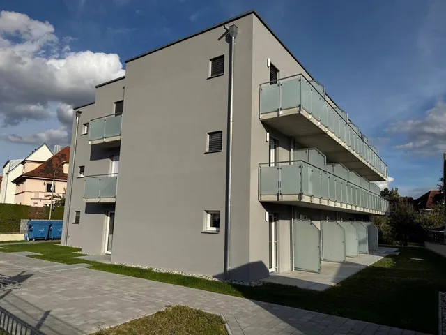 Hausecke zur Gartenseite: Rasen, Pflasterweg, Balkone mit Glasbrüstung